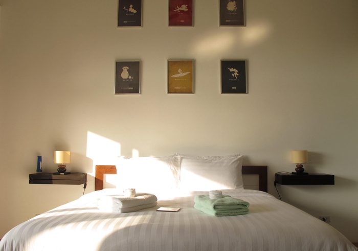 King bed and original art in a garden room at Tree Roots Retreat, Rayong