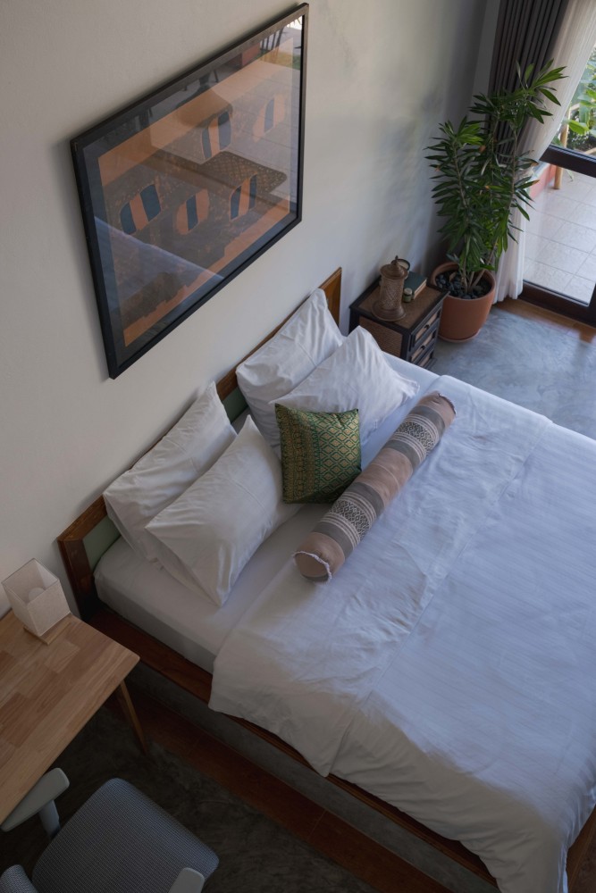 White linen pillows on a double bed beneath a green abstract painting at Tree Roots Retreat, Mae Ramphueng, Rayong.