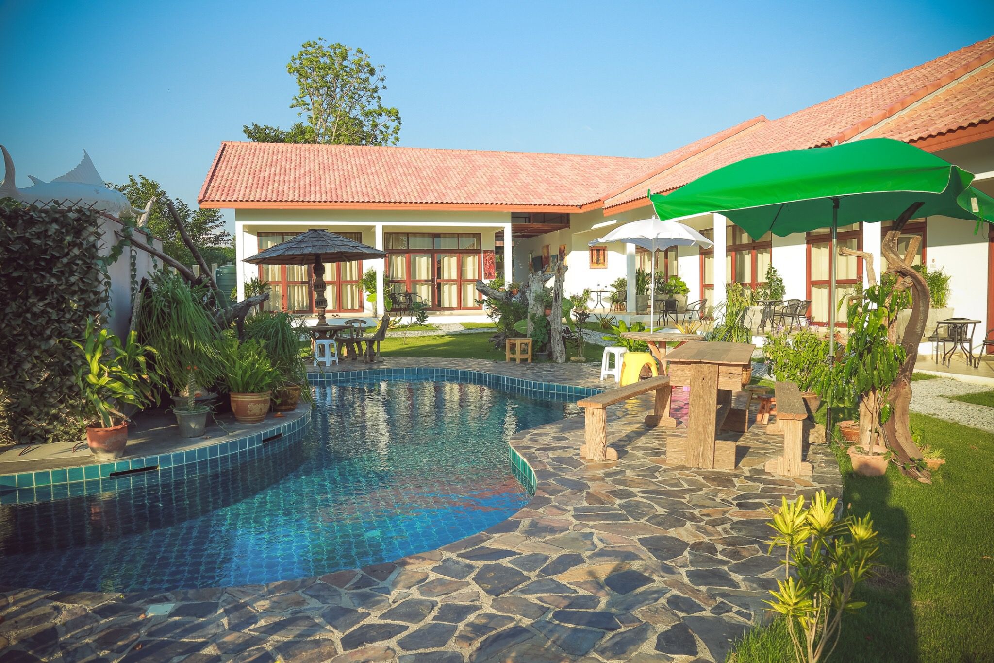 Swimming pool surrounded by tropical garden at Tree Roots Retreat, Rayong