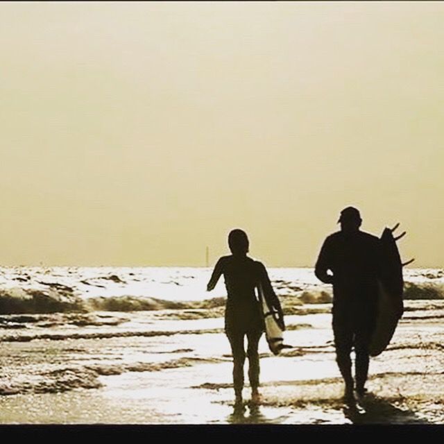 Surfers walking into the waves at sunset, Mae Ram Phueng Beach, Rayong