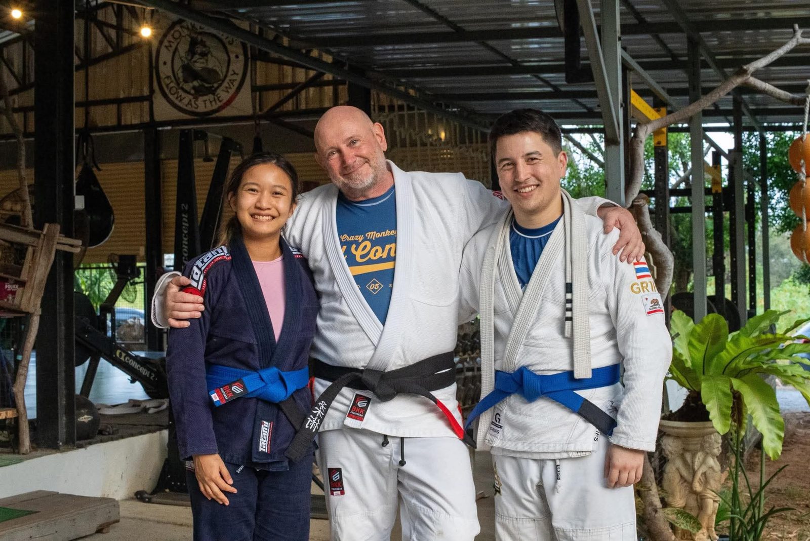 Psy with Aaron, the head coach, and Khan after a Brazilian Jiu-Jitsu session at Tree Roots Retreat in Mae Ram Phueng, Rayong &mdash; arms around each other on the mat.