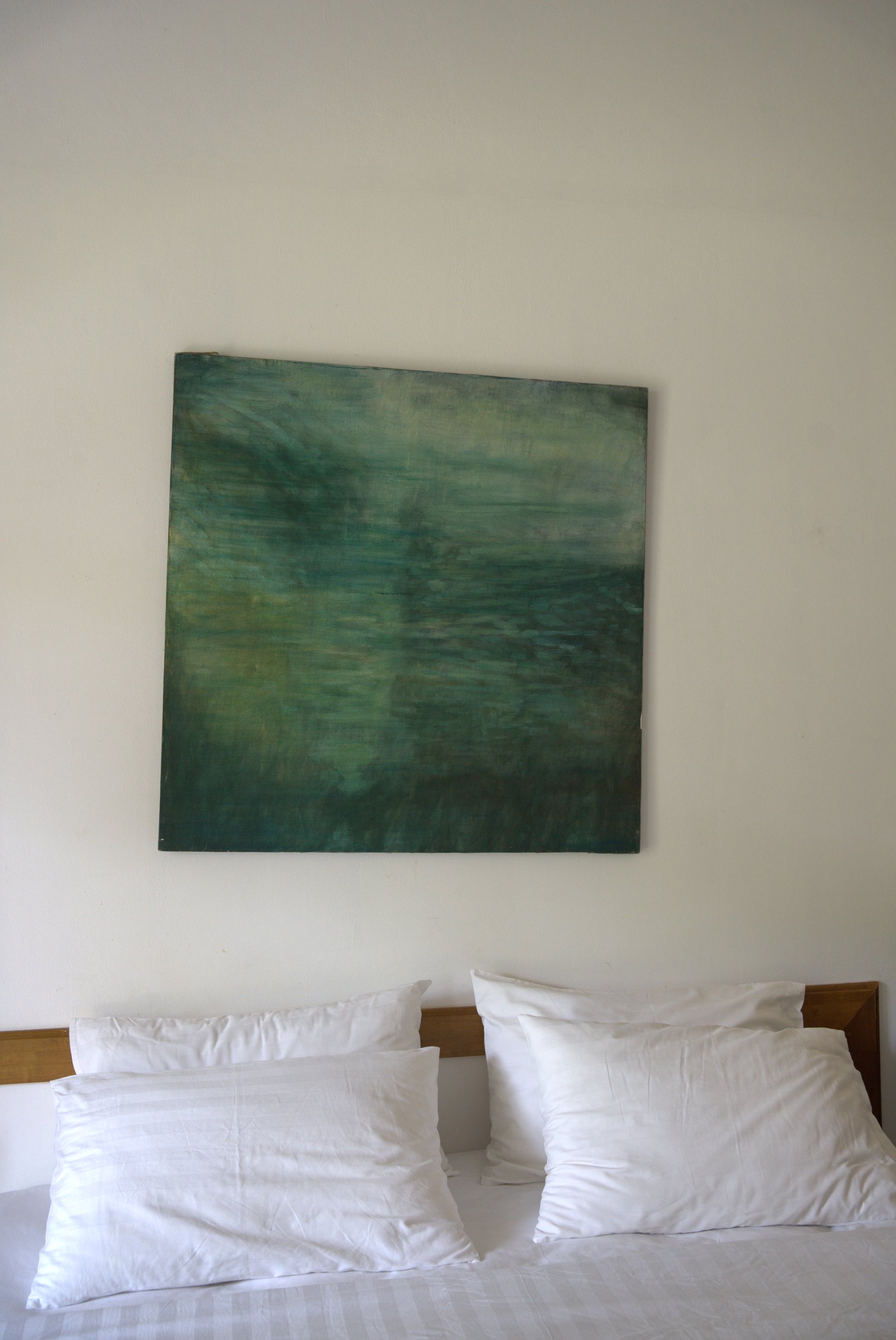 King bed in a garden room at Tree Roots Retreat, Rayong, with white linen pillows against a wooden headboard and a green canvas above.
